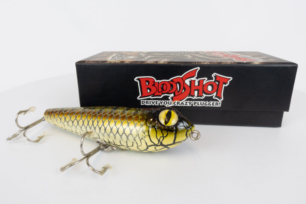 Bloodshot Raptor - Handmade Japanese Pencil Bait - Snake Skin pattern, new in original packaging, side view of fishing lure in front of packaging box. 