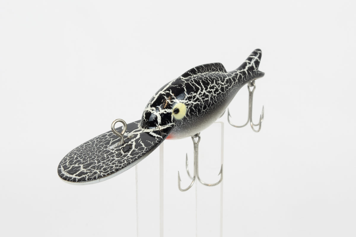 Heddon Crackleback 8000 WBC - White Black Crackle - vintage fishing lure from the USA in original packaging. View of lure on stand