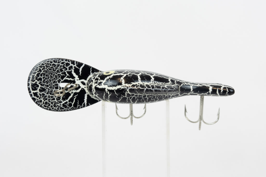 Heddon Crackleback 8000 WBC - White Black Crackle - vintage fishing lure from the USA in original packaging. Top view of lure on stand
