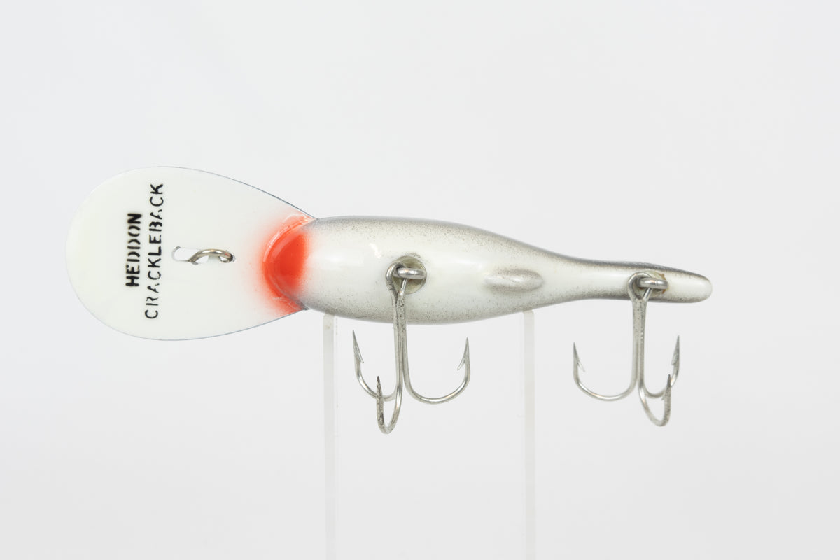 Heddon Crackleback 8000 WBC - White Black Crackle - vintage fishing lure from the USA in original packaging. Belly view of lure on stand