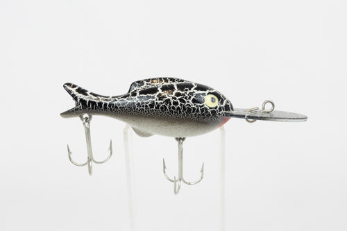Heddon Crackleback 8000 WBC - White Black Crackle - vintage fishing lure from the USA in original packaging. Right side view of lure on stand